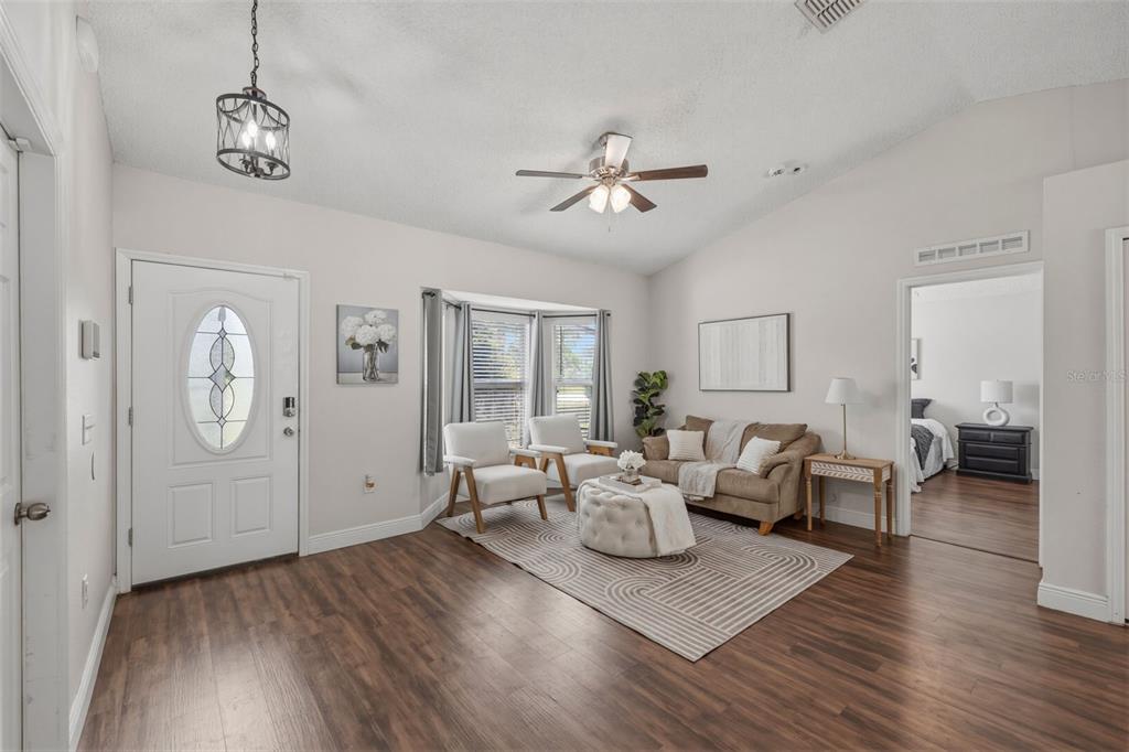 A living room features wood-look flooring, a white front door, and a bay window — 6371 SHADYDALE AVENUE, SPRING HILL, FL