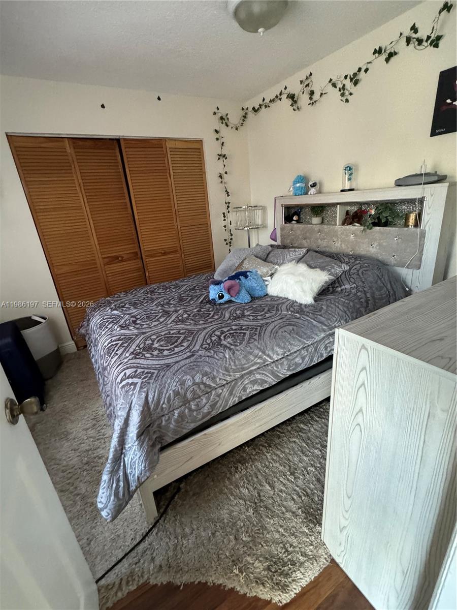 A bedroom features a bed with a gray patterned comforter, a headboard, and wood-paneled closets — 4717 NW 7th St # 10, Miami FL 33126, MIAMI, FL