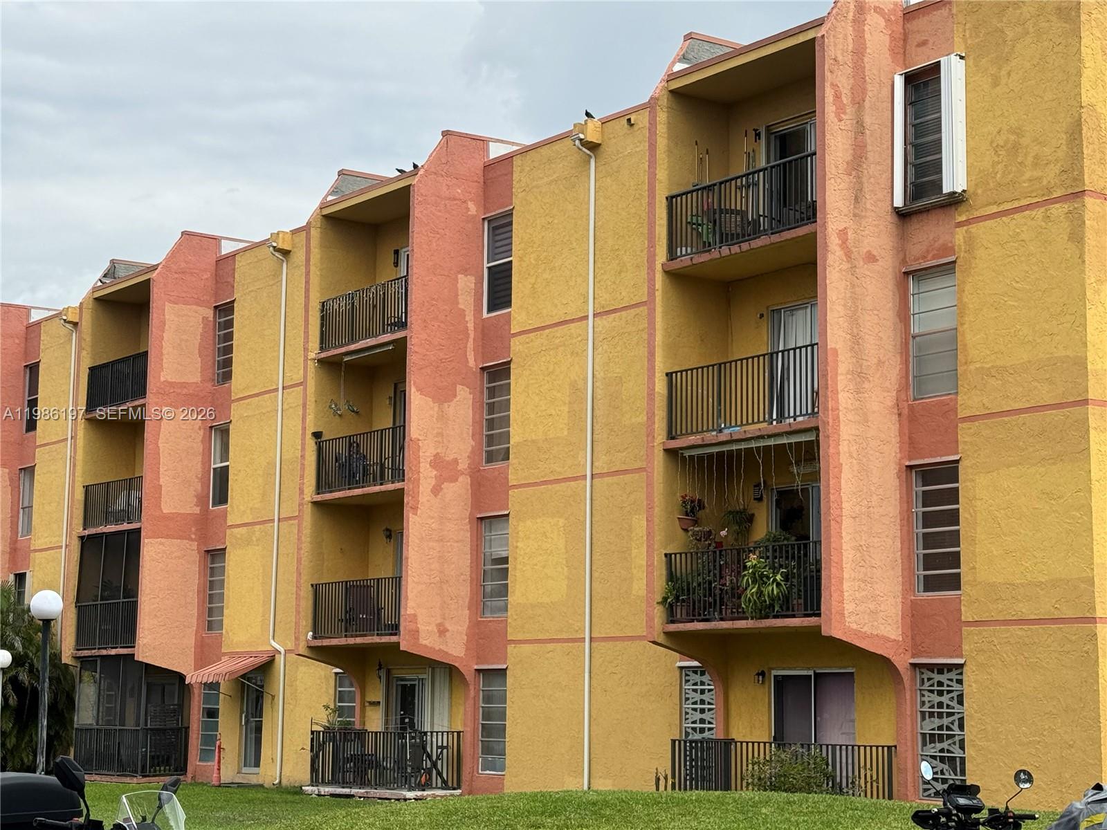 An exterior view of a multi-story apartment building with yellow and peach-colored stucco walls — 4717 NW 7th St # 10, Miami FL 33126, MIAMI, FL