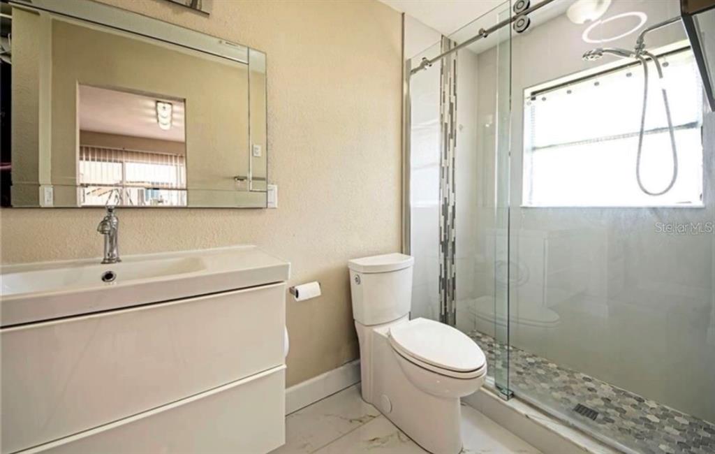 A bathroom featuring a white vanity, a toilet, and a glass-enclosed walk-in shower — 2516 BALTIC AVENUE, PORT CHARLOTTE, FL