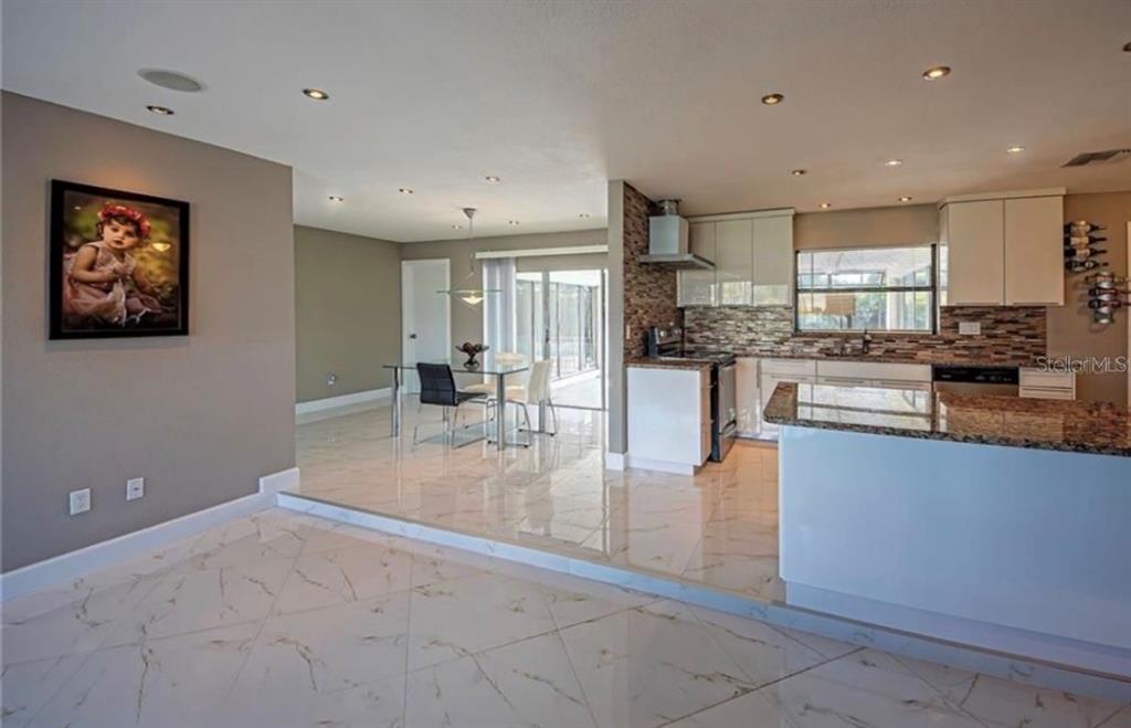 A kitchen and dining area with white tile floors, granite countertops, and a glass table — 2516 BALTIC AVENUE, PORT CHARLOTTE, FL