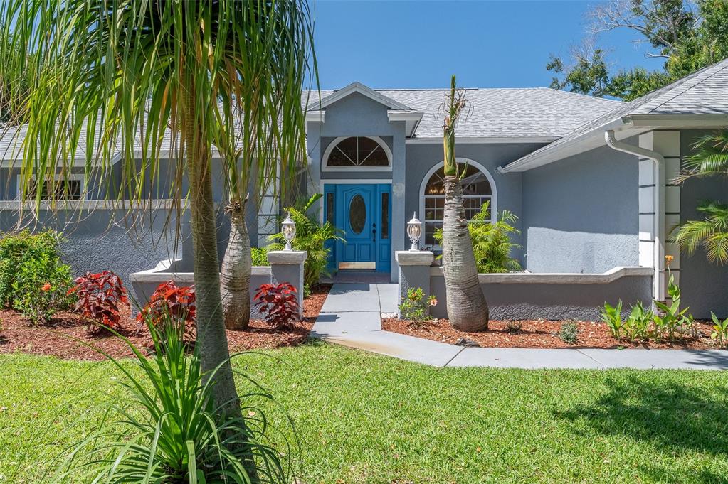 A blue front door with an arched window sits at the entrance of a gray house — 660 JILLOTUS STREET, MERRITT ISLAND, FL