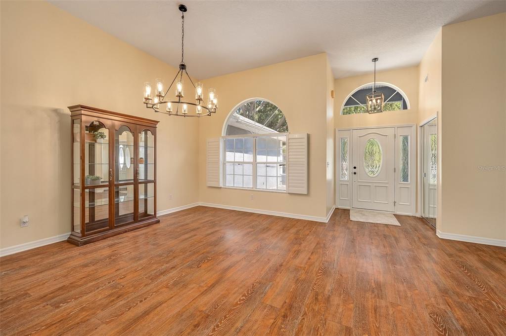 A dining room with wood-look flooring, a large hutch, and a chandelier near the entryway — 660 JILLOTUS STREET, MERRITT ISLAND, FL