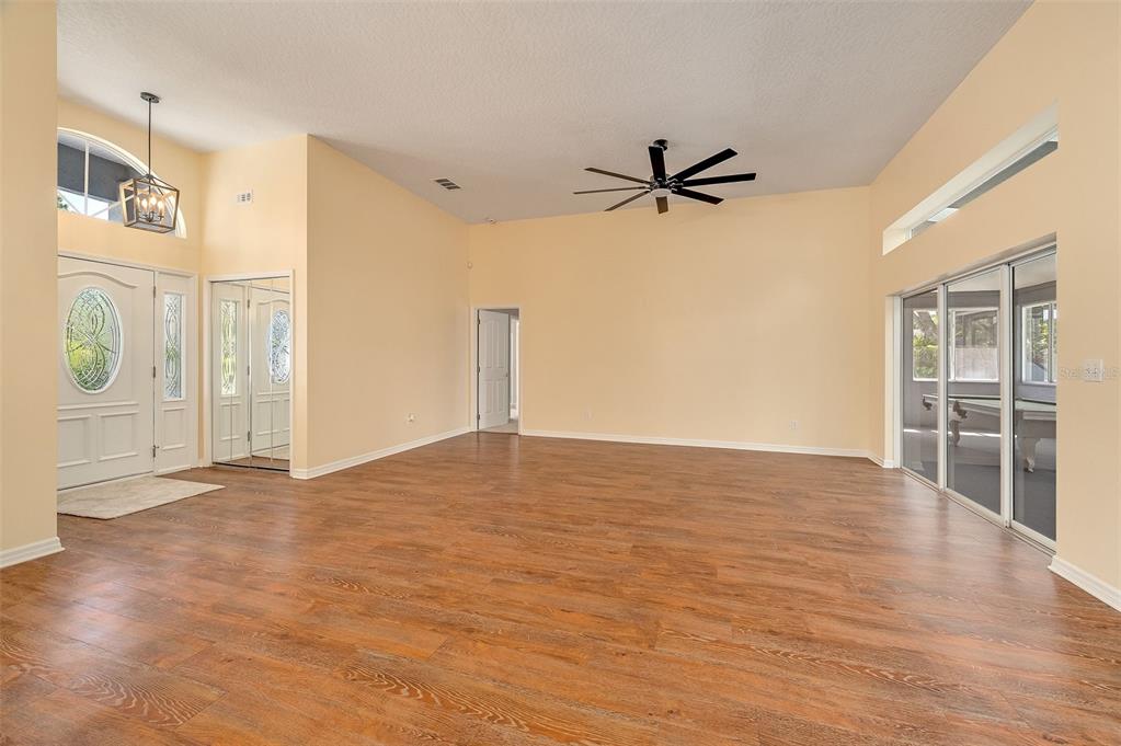 A spacious living room with high ceilings, wood-look flooring, a ceiling fan, and sliding doors — 660 JILLOTUS STREET, MERRITT ISLAND, FL