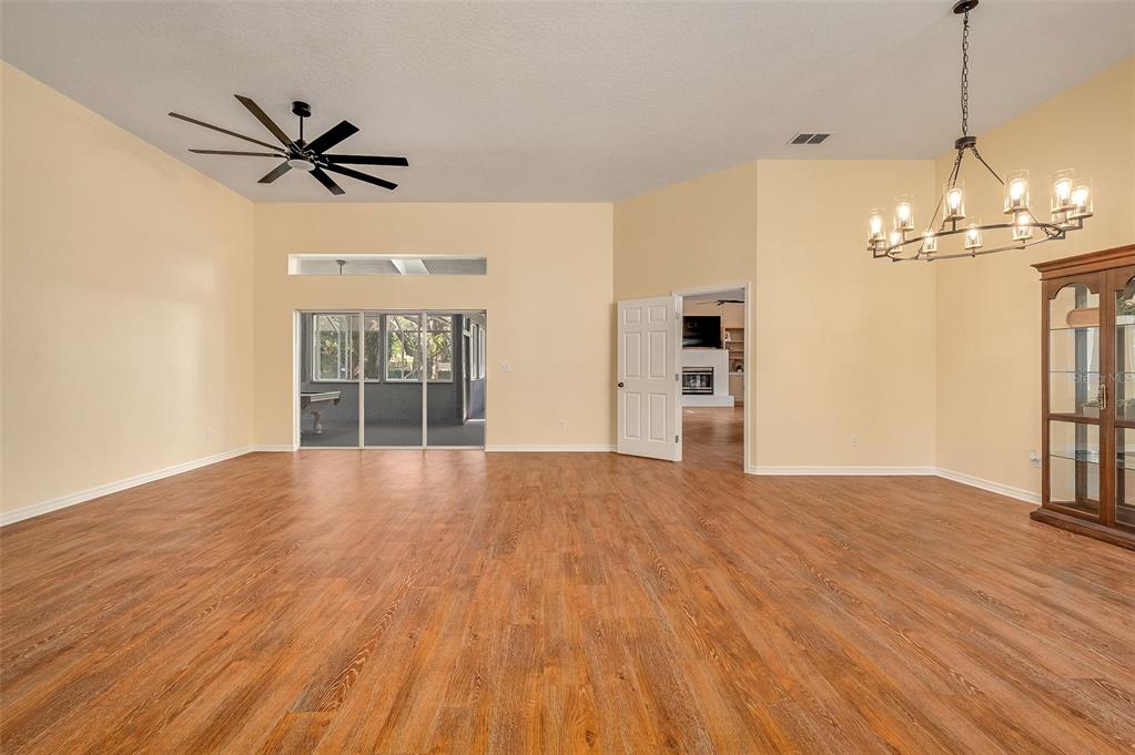 A spacious room with light yellow walls, wood-look flooring, a ceiling fan, and a chandelier — 660 JILLOTUS STREET, MERRITT ISLAND, FL