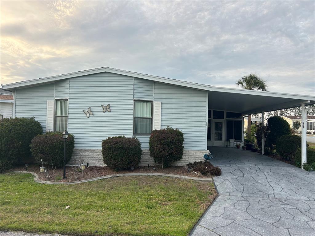 A light blue single-story home features a stone base, a carport, and a patterned driveway — 252 RITA BEE AVENUE, DAVENPORT, FL