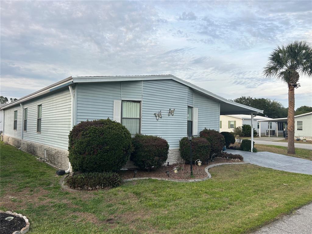 A light blue mobile home features a carport, a front lawn, and several large bushes — 252 RITA BEE AVENUE, DAVENPORT, FL