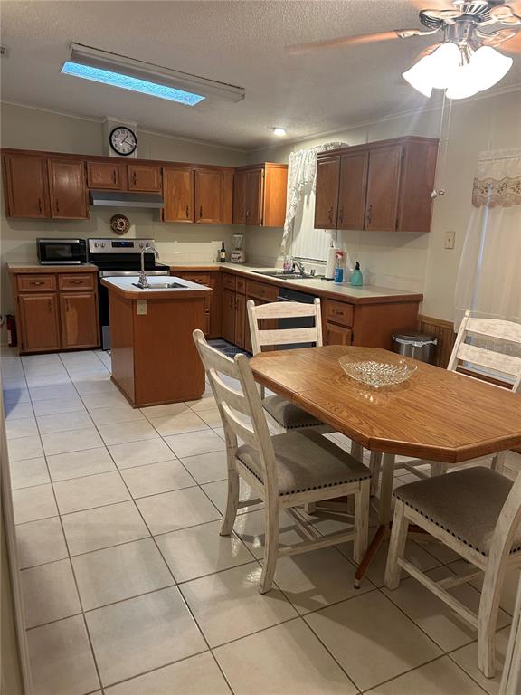 A kitchen features wood cabinets, a central island, tile flooring, and a dining table set — 252 RITA BEE AVENUE, DAVENPORT, FL