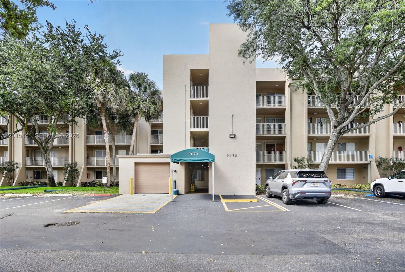 A multi-story apartment building features a green awning, a garage door, and parking spaces — 9470 Tangerine Pl # 105, Davie FL 33324, DAVIE, FL