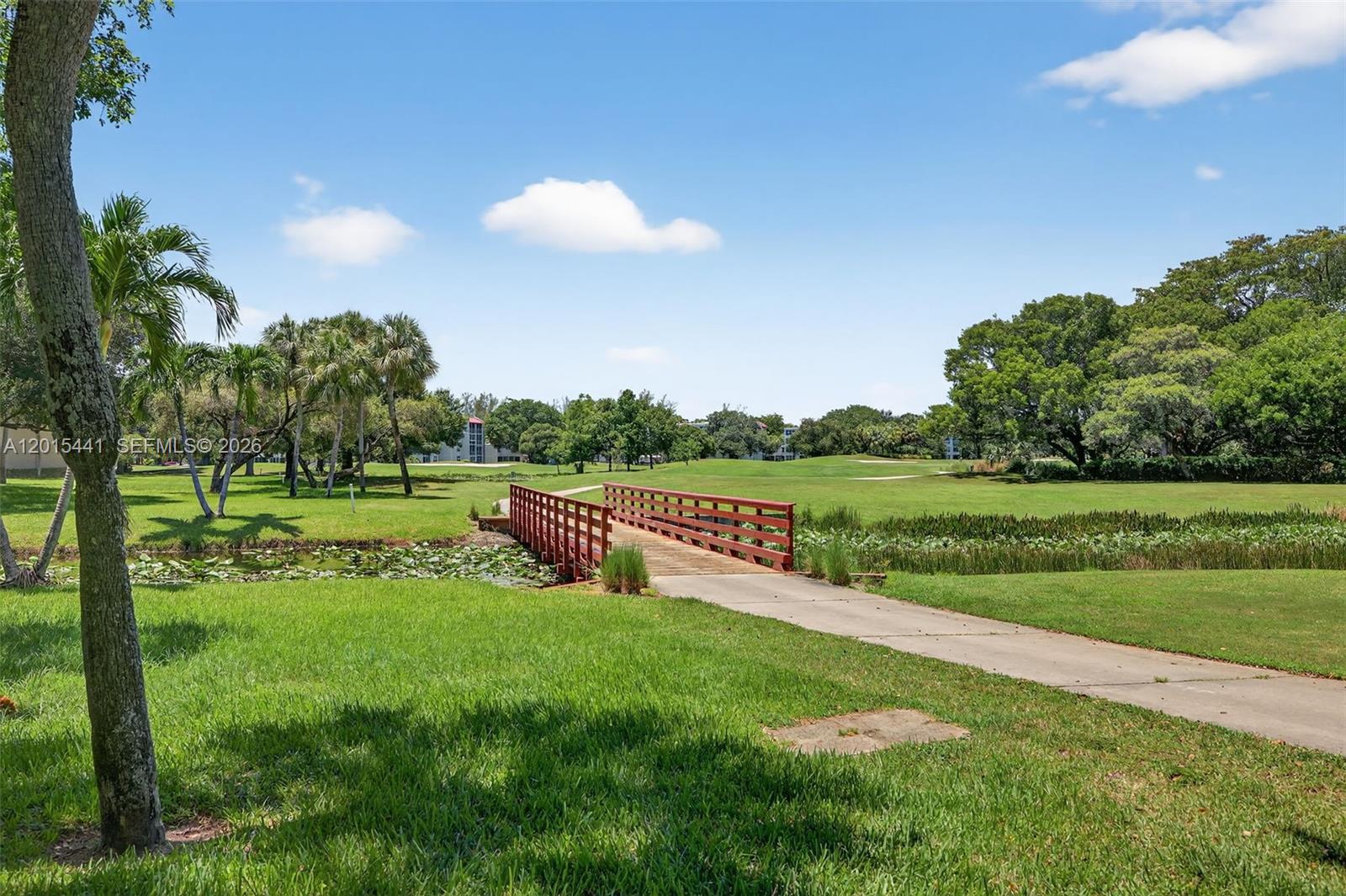 A wooden footbridge crosses a small pond on a sunny golf course landscape — 9470 Tangerine Pl # 105, Davie FL 33324, DAVIE, FL