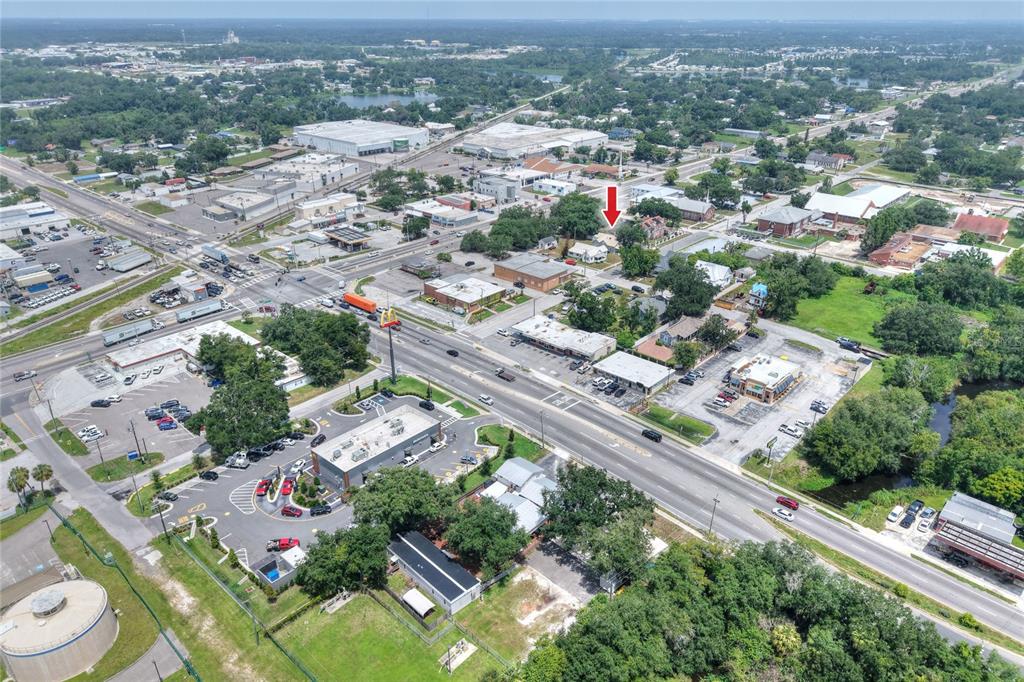 An aerial view shows a residential property marked by a red arrow near commercial businesses — 204 NE 1ST AVENUE, MULBERRY, FL