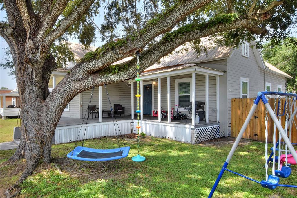 A large tree with a hanging saucer swing and climbing rope stands before a house — 204 NE 1ST AVENUE, MULBERRY, FL
