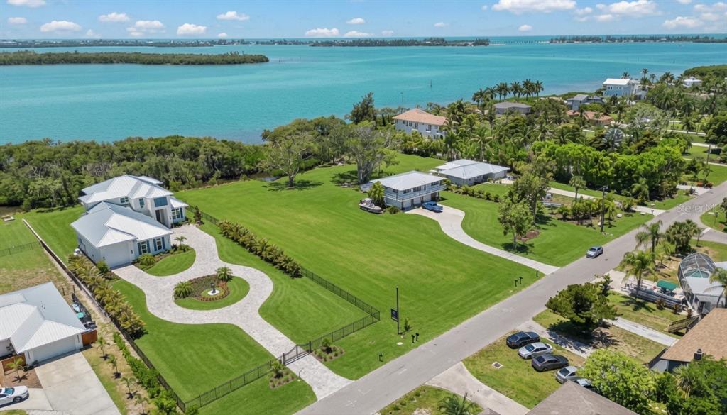 An aerial view shows two houses on a large grassy lot near a body of water — 9912 46TH AVENUE W, BRADENTON, FL