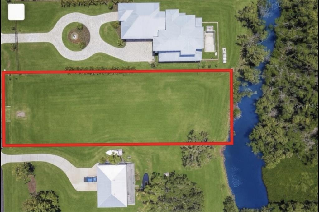 An aerial view shows a rectangular vacant lot outlined in red next to a waterway — 9912 46TH AVENUE W, BRADENTON, FL