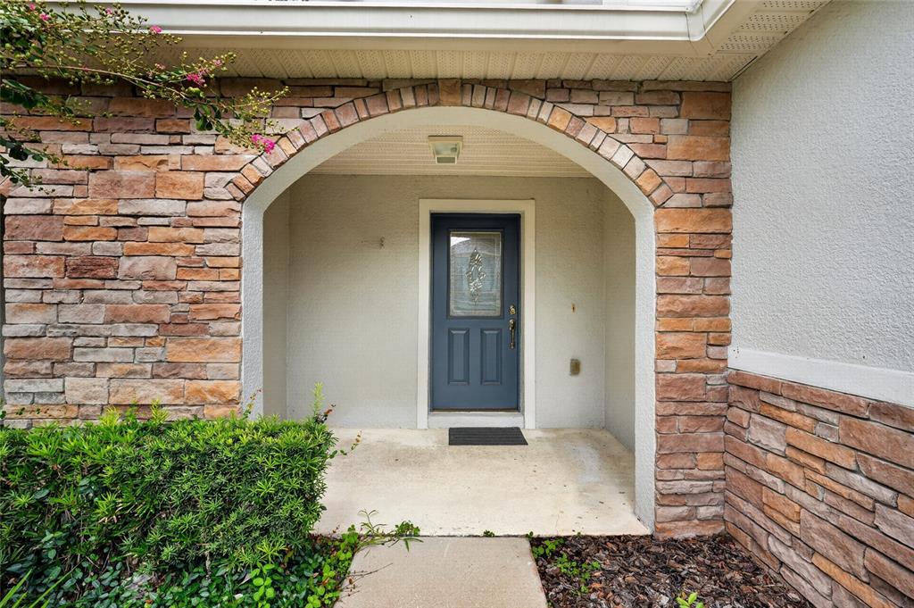 A blue front door is set within a stone-arched entryway of a residential home — 2436 HASSONITE STREET, KISSIMMEE, FL