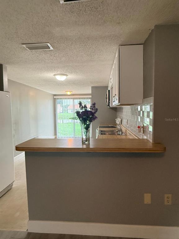 A kitchen with a wooden breakfast bar, white cabinets, and a view of a sliding door — 4212 78TH STREET W UNIT 4212, BRADENTON, FL