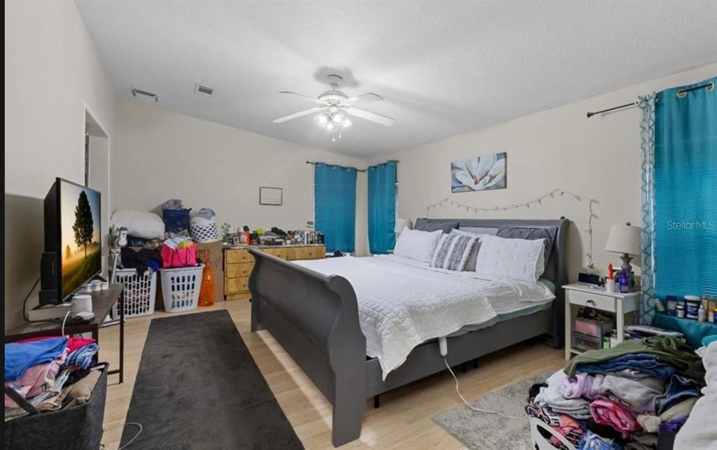 A bedroom features a gray sleigh bed, light wood flooring, and a ceiling fan — 245 NW GENELL LOOP, LAKE CITY, FL