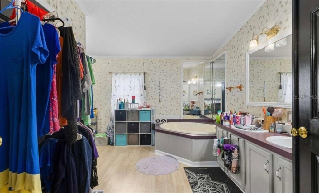 A bathroom with a jetted tub, double vanity, and an open closet area with hanging clothes — 245 NW GENELL LOOP, LAKE CITY, FL