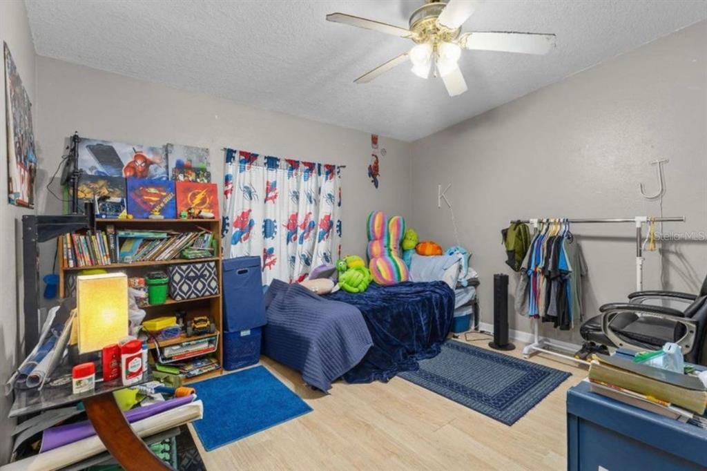 A bedroom features a bed, a bookshelf, a clothing rack, and a ceiling fan — 245 NW GENELL LOOP, LAKE CITY, FL