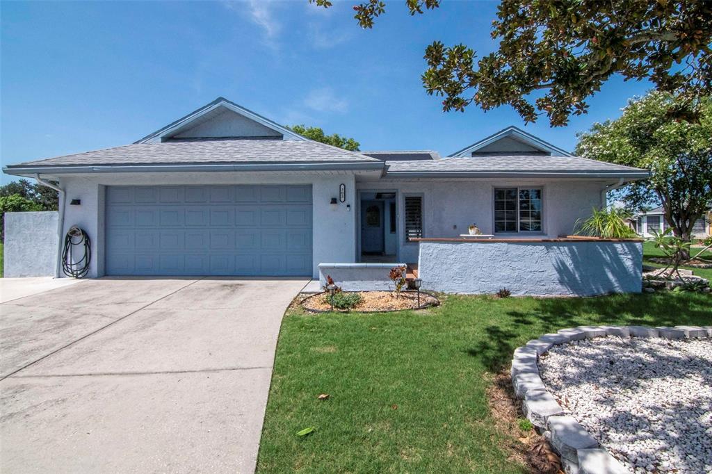 A single-story house with a blue stucco exterior, a two-car garage, and a front patio — 303 BARSTOW COURT, SUN CITY CENTER, FL