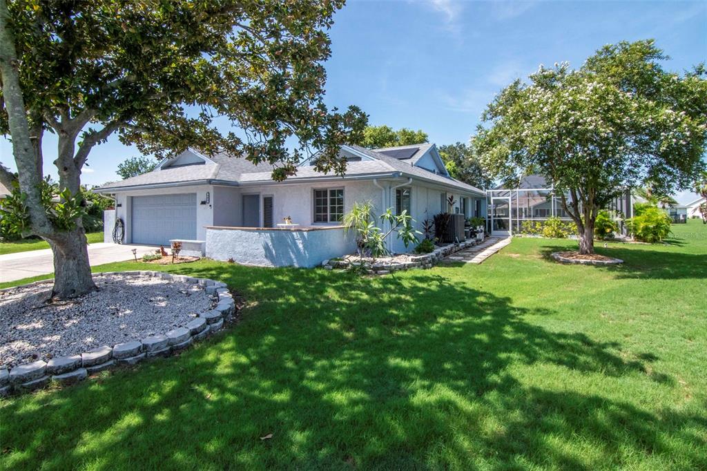A single-story house with a garage, a front patio, and a large tree-filled lawn — 303 BARSTOW COURT, SUN CITY CENTER, FL