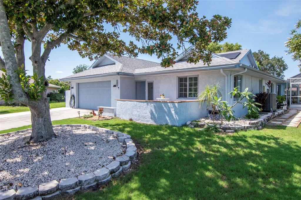 A light blue single-story house with a two-car garage, front patio, and a large tree — 303 BARSTOW COURT, SUN CITY CENTER, FL
