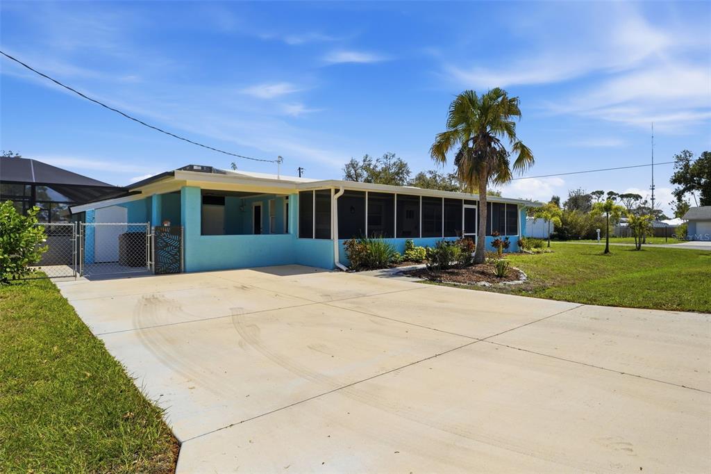 A light blue house with a screened-in porch and a concrete driveway under a blue sky — 2400 PINE COURT, NOKOMIS, FL