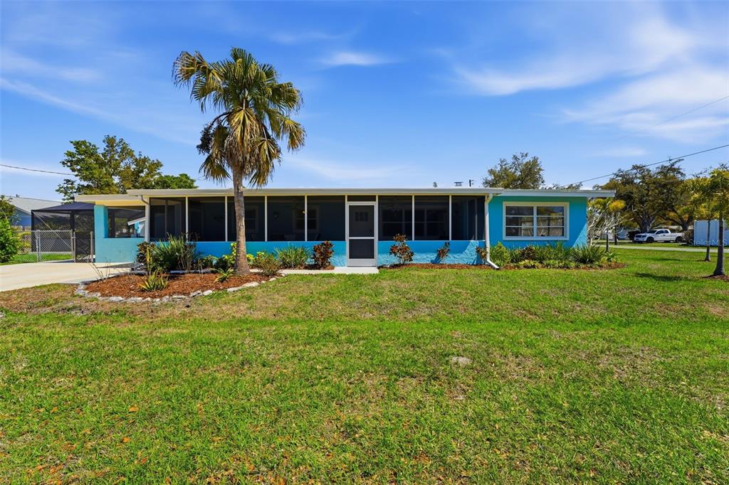 A bright blue single-story house features a screened-in front porch and a palm tree — 2400 PINE COURT, NOKOMIS, FL
