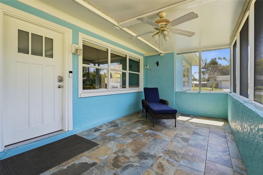 A covered porch with blue walls, tiled flooring, a ceiling fan, and a lounge chair — 2400 PINE COURT, NOKOMIS, FL