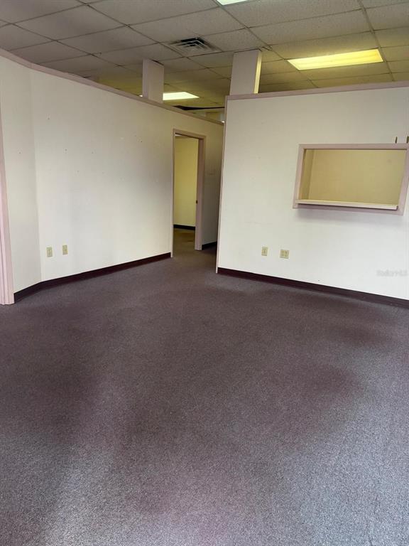 An empty office space features beige walls, dark carpet, and a service window — 6000 STATE ROAD 544, WINTER HAVEN, FL