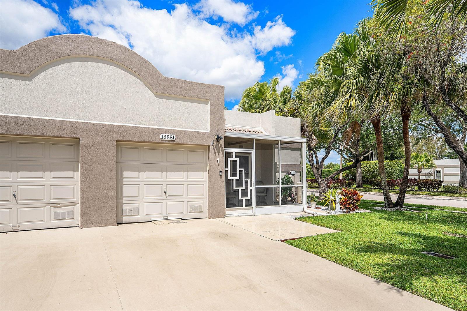 A beige stucco house features a two-car garage and a screened-in front entryway — 18881 Jolson Avenue # 1, Boca Raton FL 33496, BOCA RATON, FL