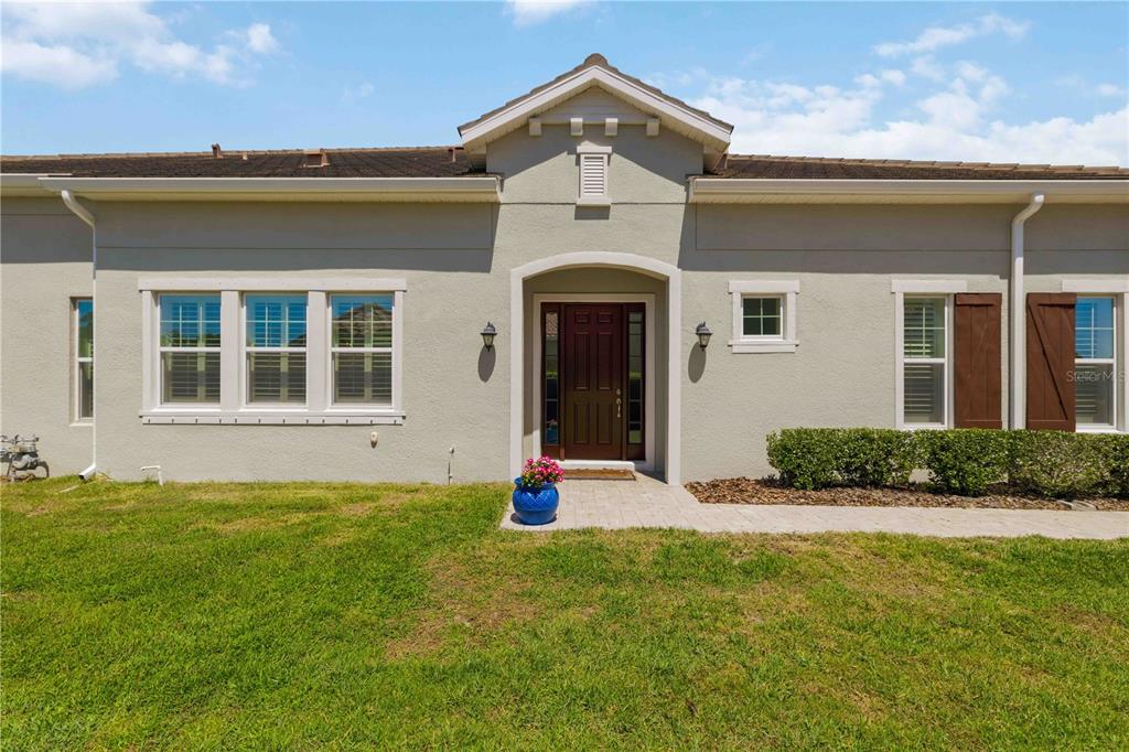 A single-story house exterior features a tan stucco facade, a brown front door, and a walkway — 2410 STARWOOD COURT, BRADENTON, FL
