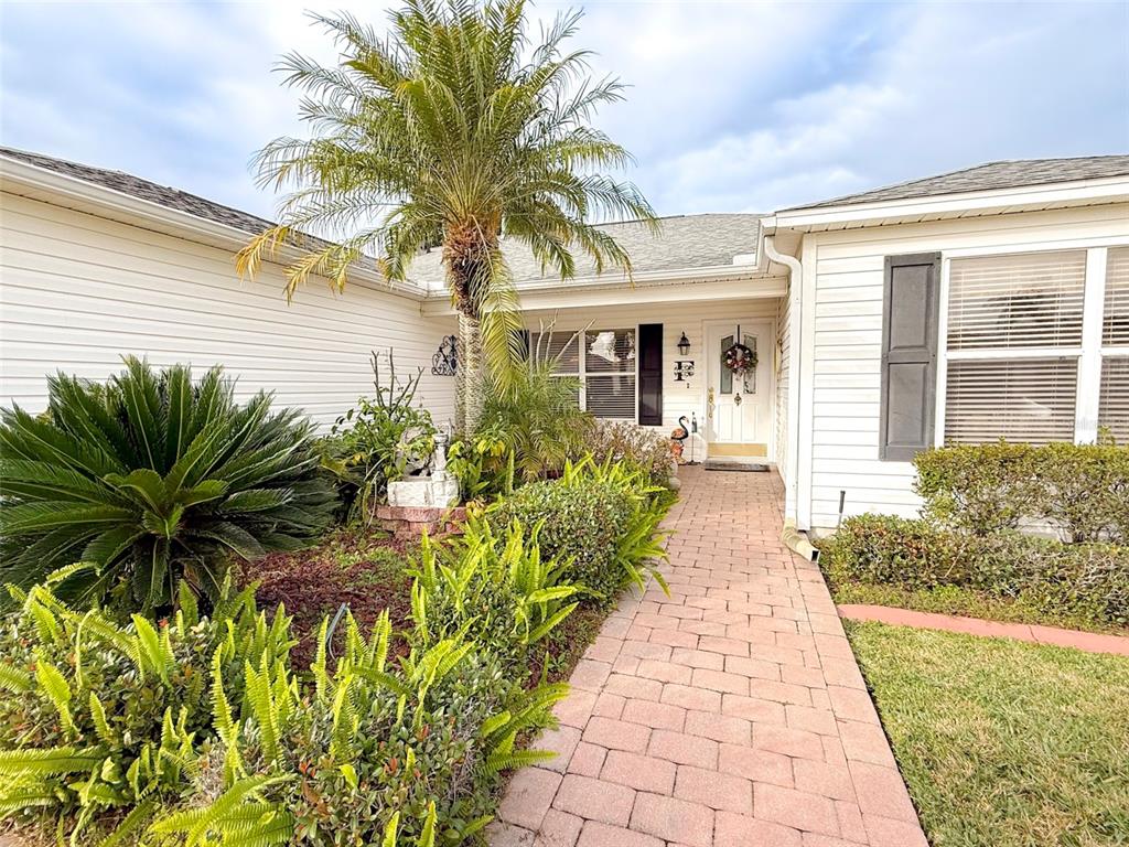 A paved walkway leads to the front entrance of a house with white siding — 8017 SE 175TH COLUMBIA PLACE, THE VILLAGES, FL