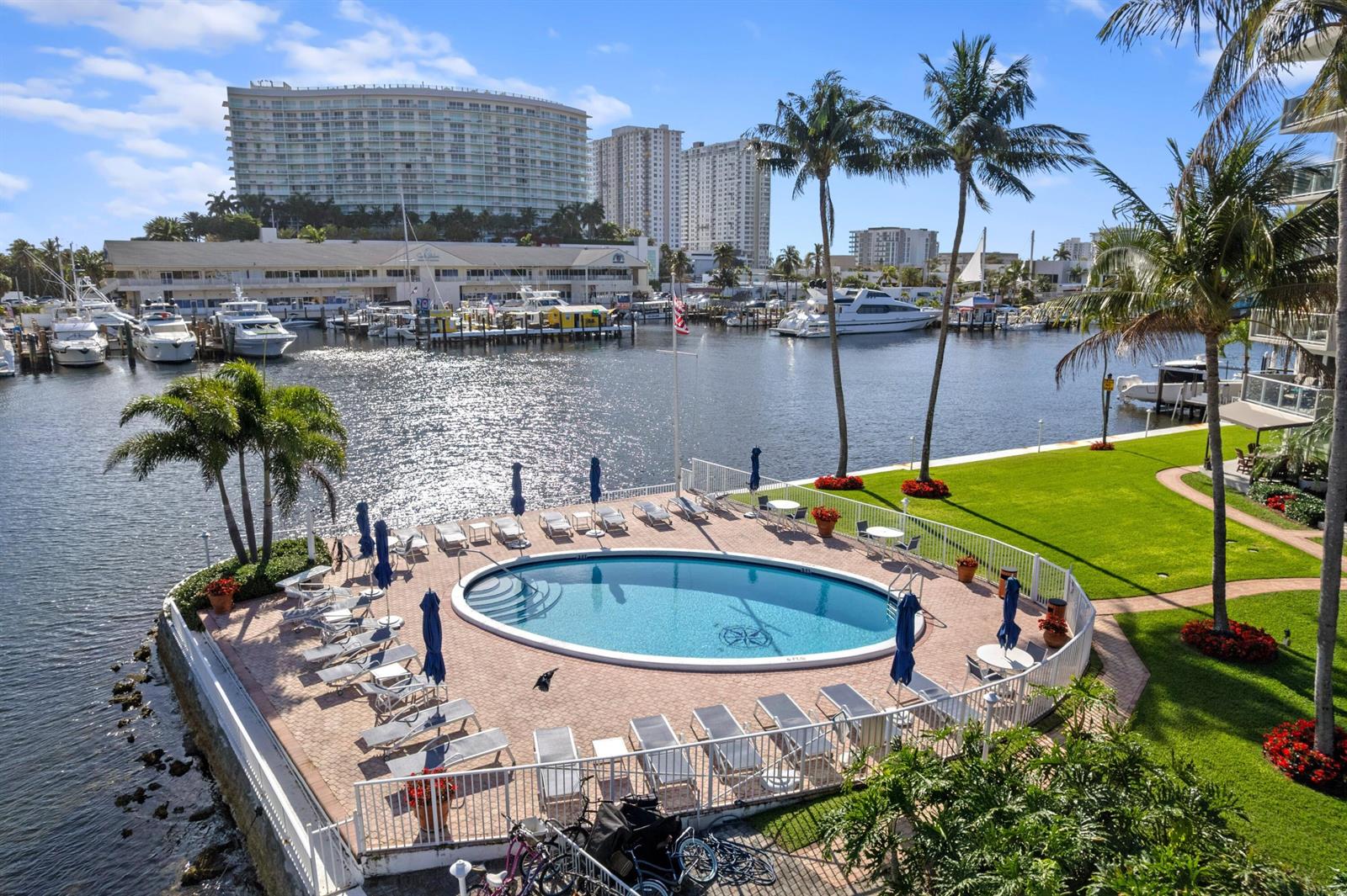 An elevated view of a circular swimming pool on a brick patio overlooking a marina — 140 NE 28th # 604, Pompano Beach FL 33062, POMPANO BEACH, FL