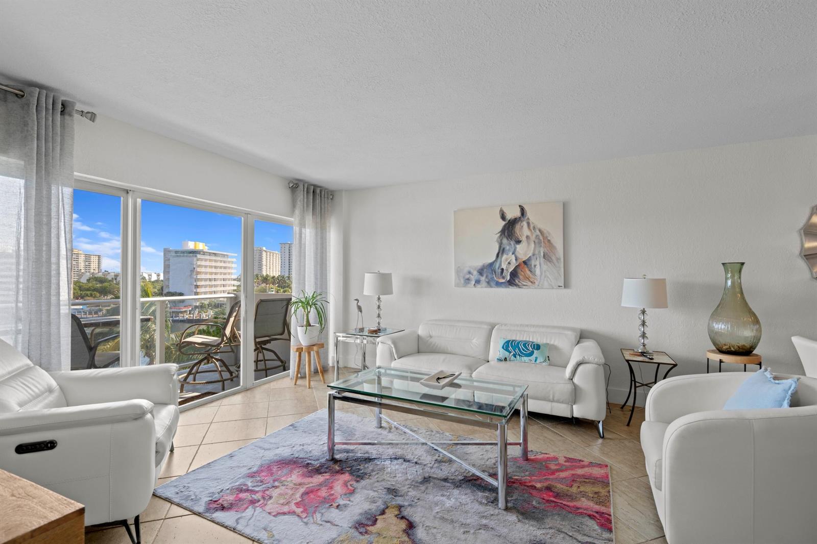 A living room with white leather furniture, a glass coffee table, and a balcony view — 140 NE 28th # 604, Pompano Beach FL 33062, POMPANO BEACH, FL