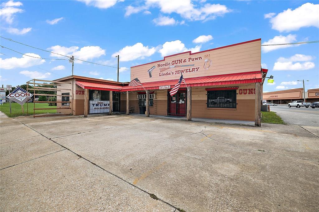 A single-story commercial building with a red metal awning, signage for a pawn shop, and parking — 324 S MAIN STREET, WILDWOOD, FL