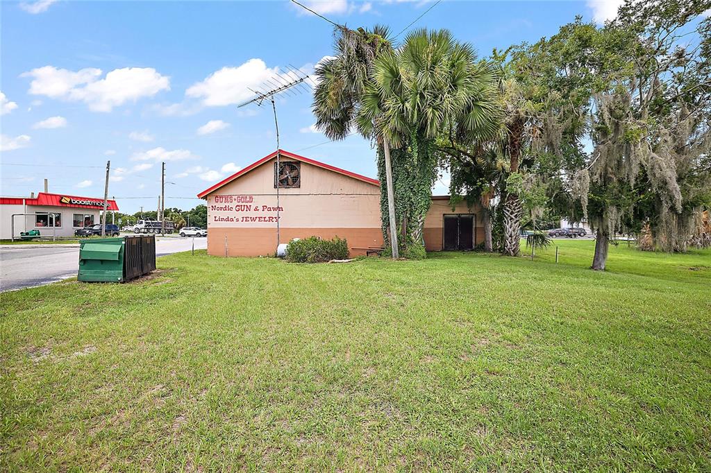 A small, tan commercial building with a red roof sits on a grassy lot — 324 S MAIN STREET, WILDWOOD, FL