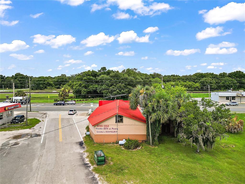 An aerial view shows a small commercial building with a red roof near a road — 324 S MAIN STREET, WILDWOOD, FL