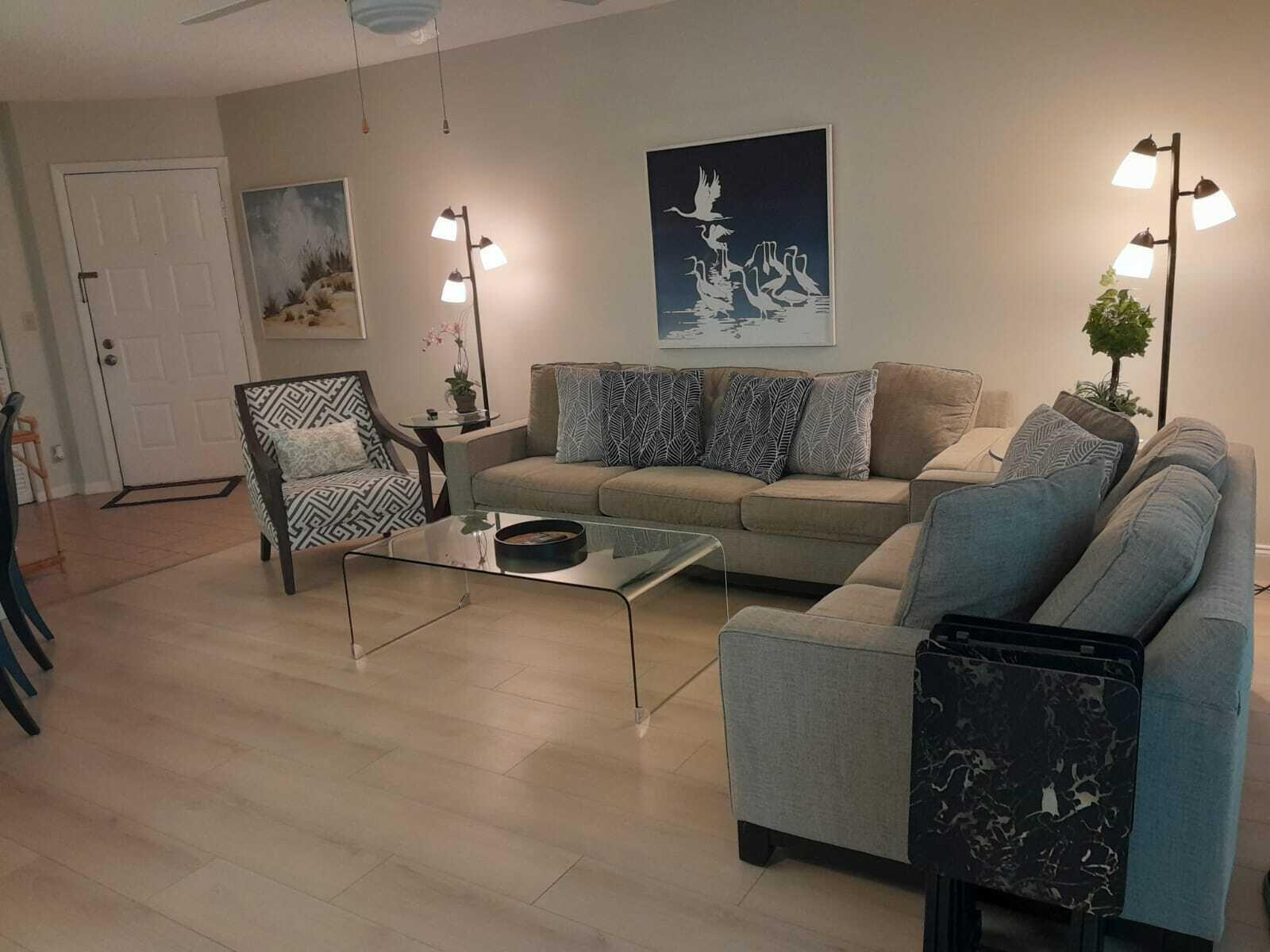 A living room features a beige sofa, a patterned armchair, and a glass coffee table — 1605 S Us Highway 1 # C302, Jupiter FL 33477, JUPITER, FL