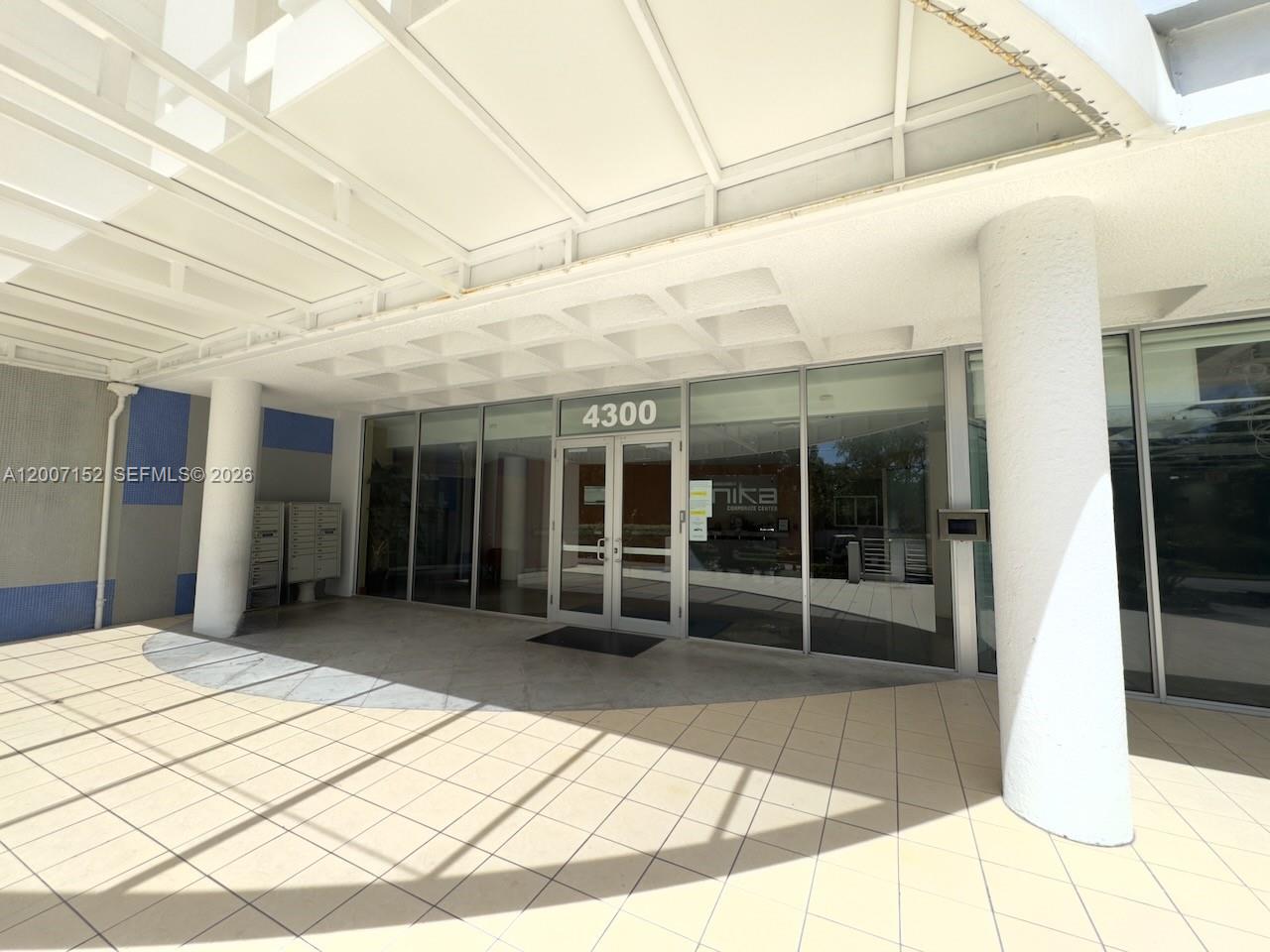 The exterior entrance of a commercial building features glass doors, tiled flooring, and a canopy — 4300 Biscayne Blvd # 206, Miami FL 33137, MIAMI, FL