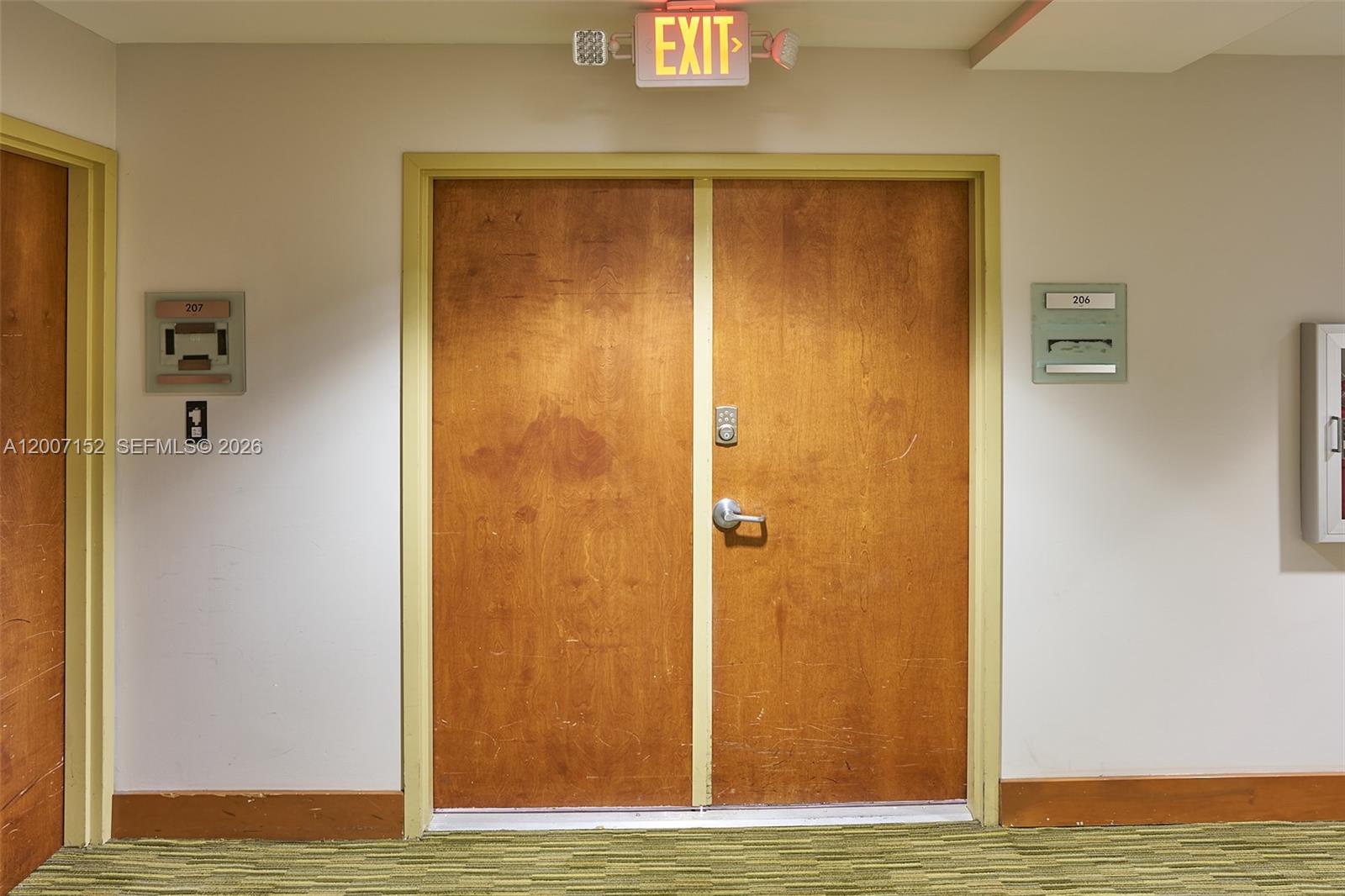 A hallway features double wooden doors with an exit sign above and room numbers nearby — 4300 Biscayne Blvd # 206, Miami FL 33137, MIAMI, FL