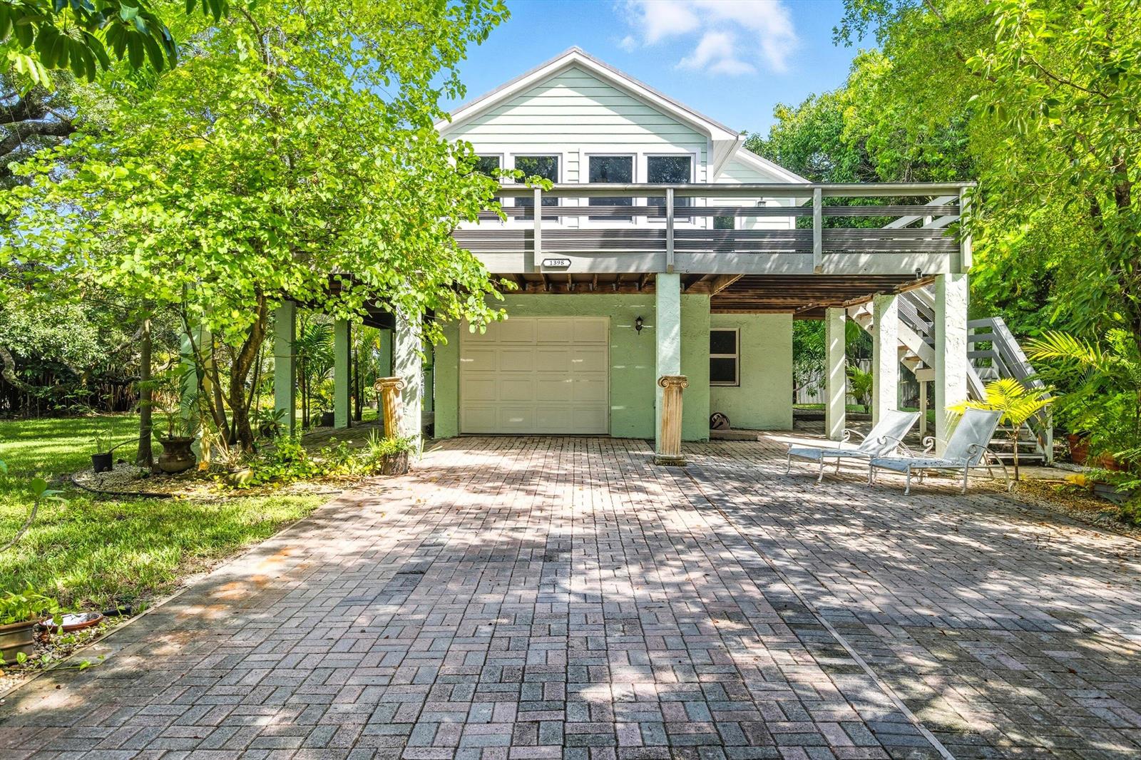 A two-story house with a light green exterior, a raised deck, and a paved driveway — 1398 SW Palm City Road, Stuart FL 34994, STUART, FL