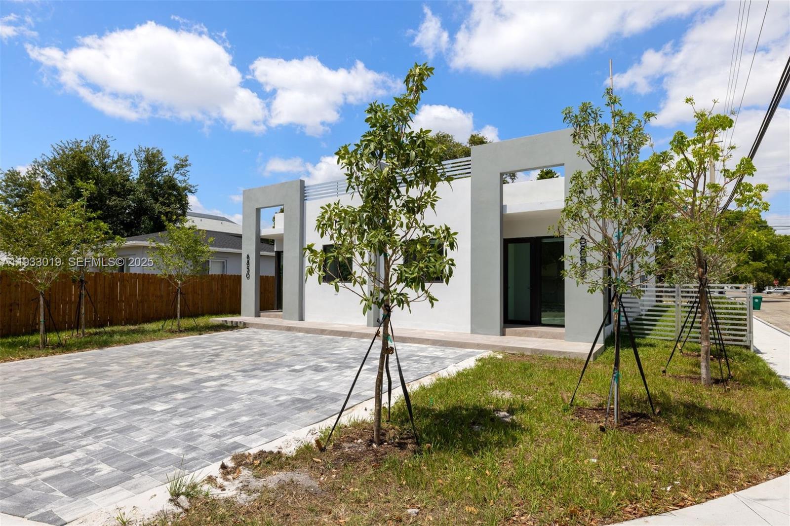 A modern, white single-story house features gray accents, a paved driveway, and young trees — 6852-6850 NW 4th AVE, Miami FL 33150, MIAMI, FL