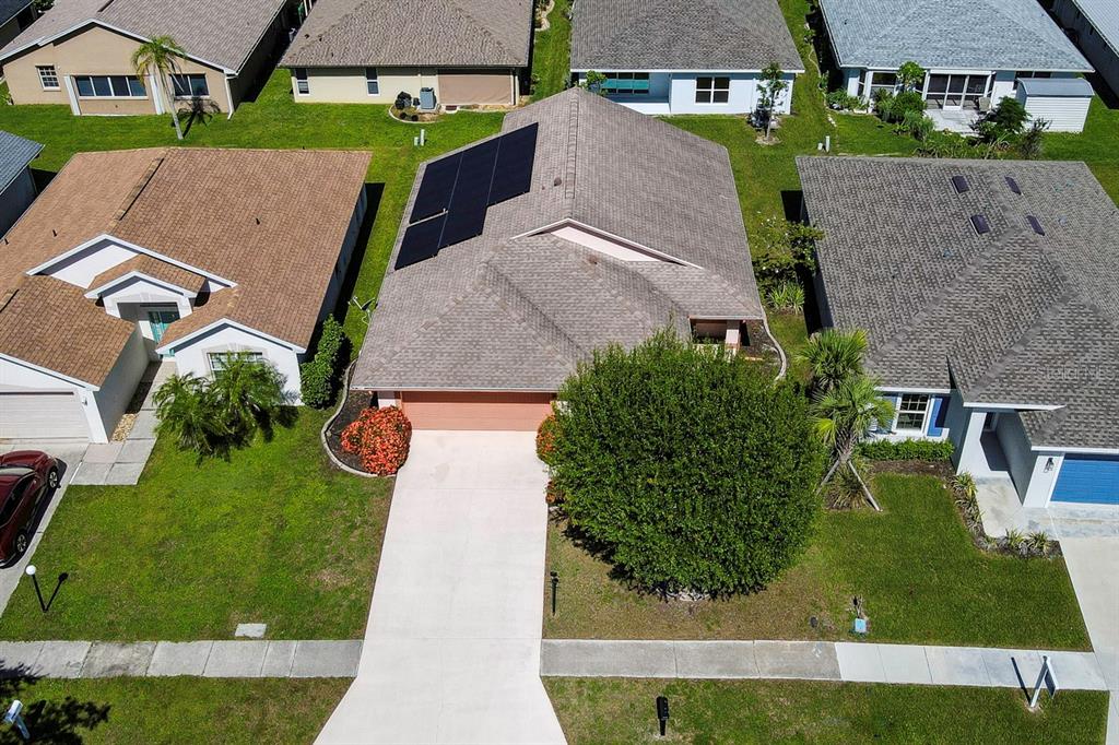 An aerial view shows a suburban house with a solar panel array on the roof — 483 WINWOOD COURT, PORT CHARLOTTE, FL