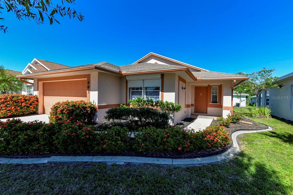 A single-story house with a tan exterior, orange trim, and a landscaped front yard — 483 WINWOOD COURT, PORT CHARLOTTE, FL