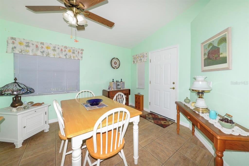 A dining room with light green walls, tile flooring, a wooden table, and a ceiling fan — 483 WINWOOD COURT, PORT CHARLOTTE, FL