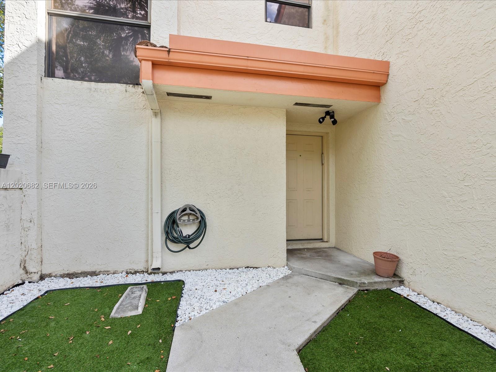 A concrete walkway leads to the front door of a home with an orange awning — 3400 Emerald Oaks Dr # 801, Hollywood FL 33021, HOLLYWOOD, FL