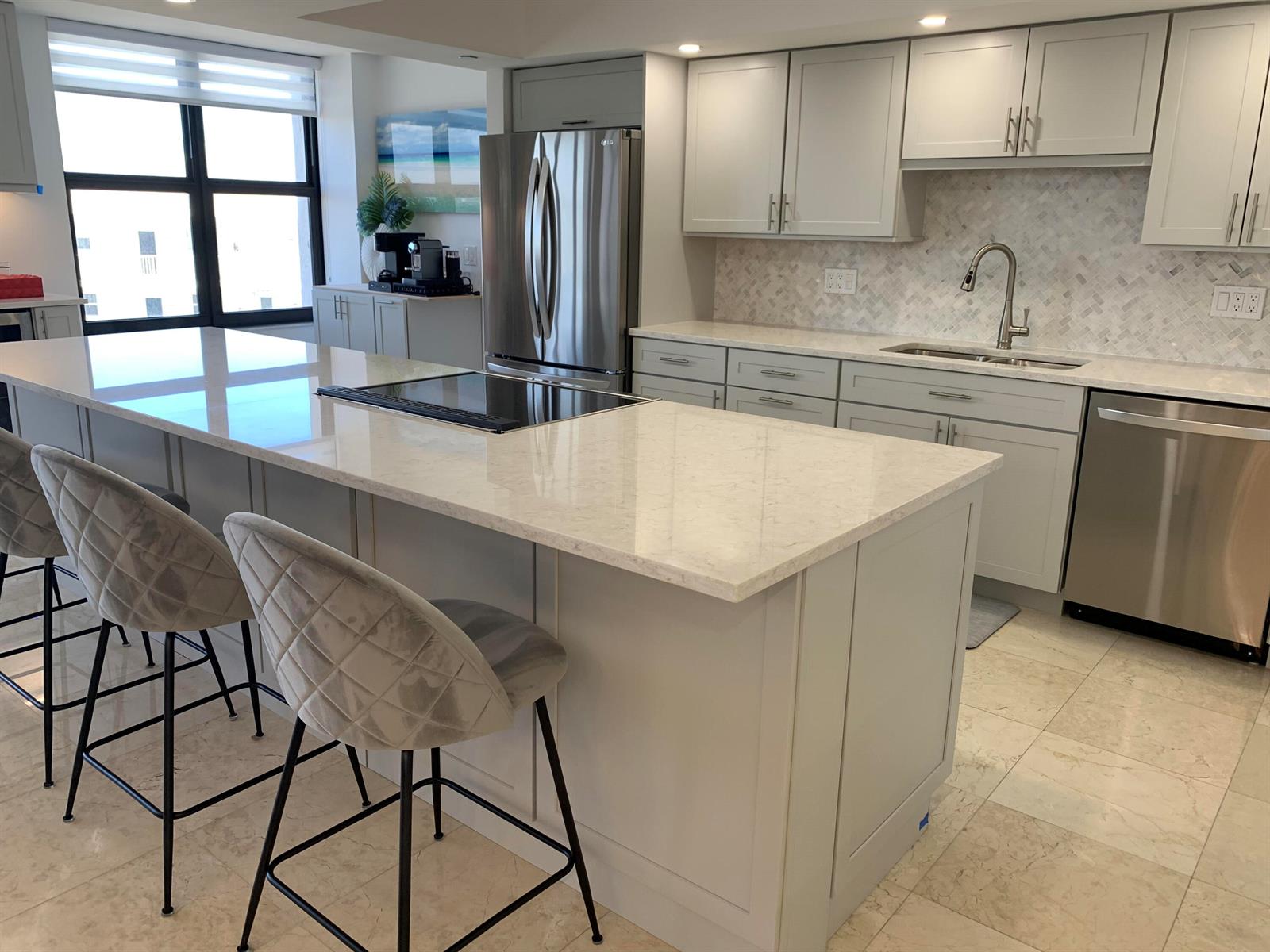 A modern kitchen features light gray cabinets, a large quartz island, and stainless steel appliances — 3115 S Ocean Boulevard # 1002, Highland Beach FL 33487, HIGHLAND BEACH, FL