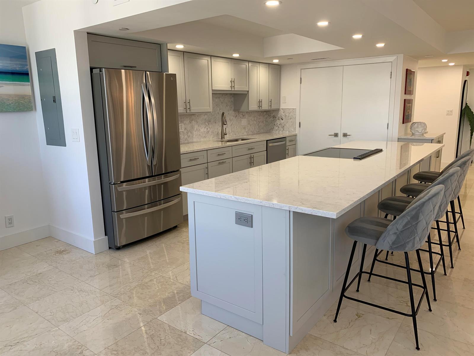 A modern kitchen features light gray cabinets, stainless steel appliances, and a large marble-topped island — 3115 S Ocean Boulevard # 1002, Highland Beach FL 33487, HIGHLAND BEACH, FL