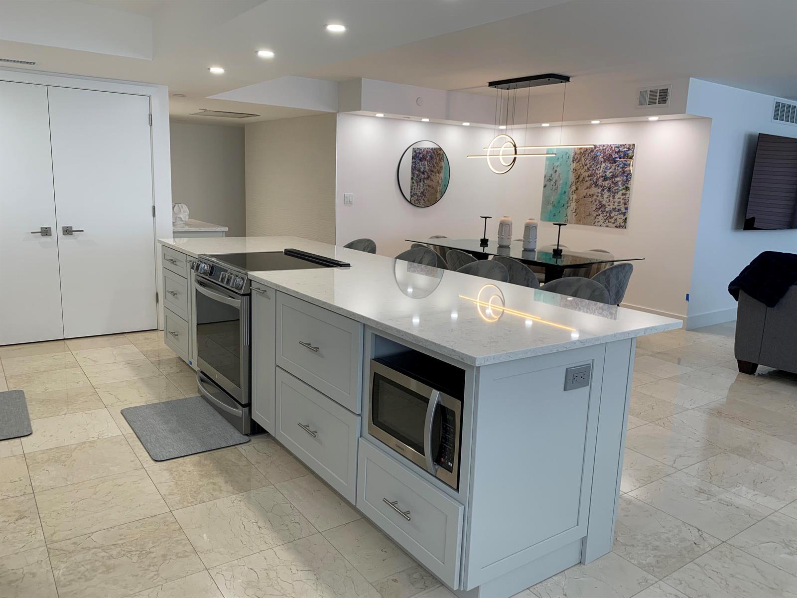 A modern kitchen island with a built-in oven and microwave sits on a tiled floor — 3115 S Ocean Boulevard # 1002, Highland Beach FL 33487, HIGHLAND BEACH, FL
